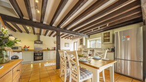 A kitchen with wooden beams, a stainless steel refrigerator, and a dining table with chairs. - The Granary, Oulton, Norfolk (Oulton)