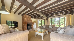 A cozy living room with a fireplace, comfortable sofas, and a television. - The Granary, Oulton, Norfolk (Oulton)