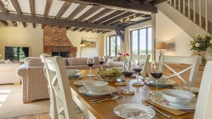 A dining area with a wooden table set for a meal, a fireplace, and a staircase. - The Granary, Oulton, Norfolk (Oulton)