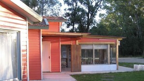 A red house with a covered patio and a lawn. - Posada María Cristina (Punta del Este)