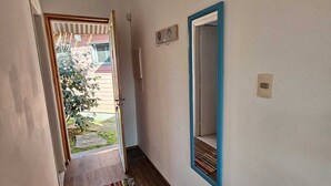 A hallway with wooden flooring, a blue-framed mirror, and a small rug. - Posada María Cristina (Punta del Este)