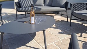Un espace patio avec une table ronde, une bouteille de vin et deux verres.