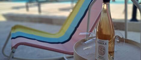 A bottle of Château Yssole wine on a small round table with a metal frame, placed on a tiled floor.