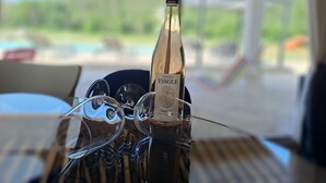 Une bouteille de vin Château Ysssole, avec son étiquette, est posée sur une table. On peut voir, en arrière-plan, une piscine et un espace de détente extérieur.