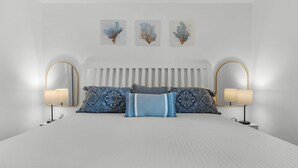 A modern bedroom with a large bed, two bedside lamps, and three wall-mounted artworks.