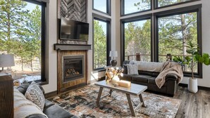 Amplia sala de estar con chimenea, ventanas grandes, un sofá y una mesa de centro.