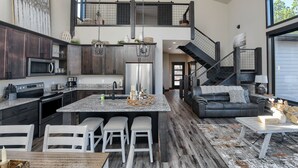 Una cocina moderna con armarios de madera oscura, electrodomésticos de acero inoxidable y una isla central con taburetes.