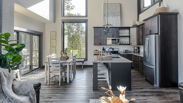 Una cocina moderna con una isla central, armarios oscuros y un amplio ventanal que proporciona luz natural.