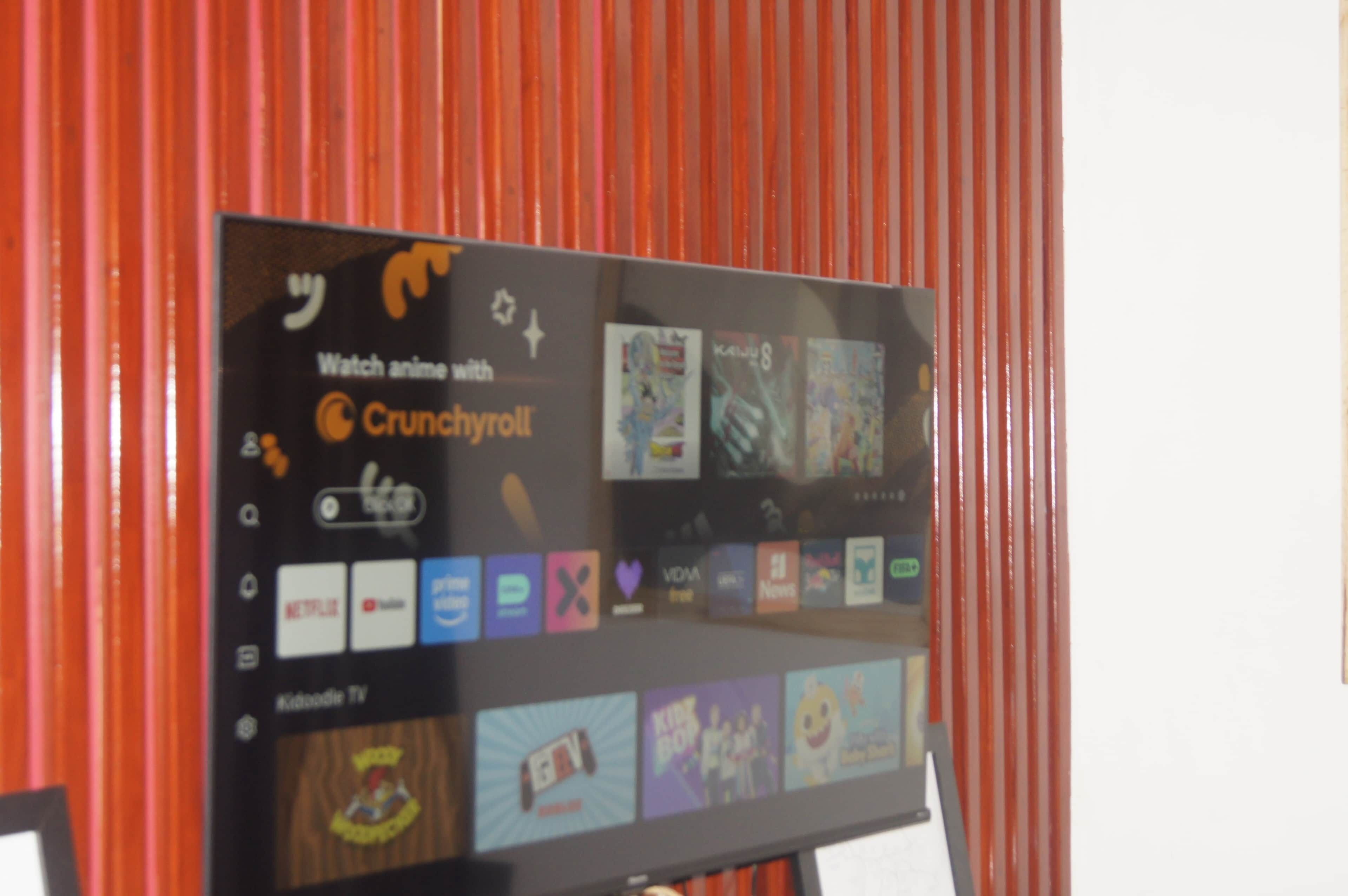 A flat-screen TV mounted on a wall displaying various streaming services and channels.