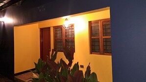 A building with a yellow exterior, wooden doors, and windows with metal grilles.