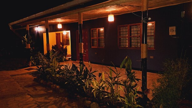 A house with a porch, potted plants, and a warm light.