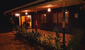 A house with a porch, potted plants, and a warm light. - Blue Cactus Shanty (Moshi Urban)