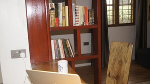 A wooden bookshelf filled with books, a laptop on a table, and a chair.