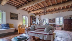 A rustic living room with exposed wooden beams, a sofa, a coffee table, and a bookshelf.