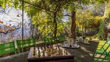Guests can play a game of chess in a serene outdoor setting surrounded by lush greenery.