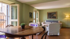 Un coin repas avec une table et des chaises en bois, une plante en pot et un canapé avec une couverture.