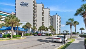 A hotel with multiple high-rise buildings, a parking lot, and palm trees.
