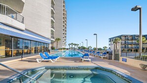 A hotel pool area with lounge chairs and a hot tub.