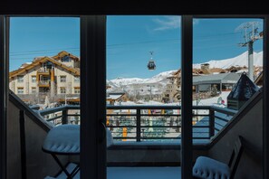 A view from a balcony with a chair, a ski lift, and buildings in the background. - Mountain Blue Mesa Condo by InvitedHome | Ski-In/Ski-Out, Village Core, Walkable (Telluride)