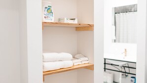 Une salle de bain avec des étagères en bois où sont rangées les serviettes et les articles de toilette.