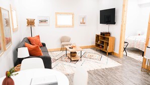 Un salon moderne comprenant un canapé, une table basse, un téléviseur et une bibliothèque.