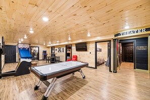 A wooden interior with a pool table, arcade games, a billiards table, and a cinema sign.