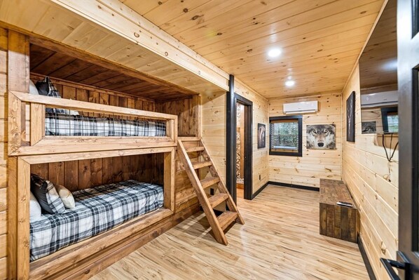 A cabin with a bunk bed, a staircase, and a small table.