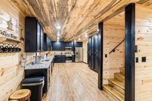 A kitchen with wooden walls, a central island, and a staircase leading to another level.