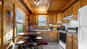 A wooden cabin-style kitchen with a central island, wooden cabinets, a refrigerator, and a stove. - 1mi From Parkway ~ Hot Tub ~ Fire Place (Gatlinburg)