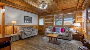 A cozy cabin interior with a wooden ceiling, two sofas, a coffee table, and a fireplace. - 1mi From Parkway ~ Hot Tub ~ Fire Place (Gatlinburg)