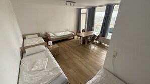 A room with three wooden beds, a wooden dining table, and chairs.