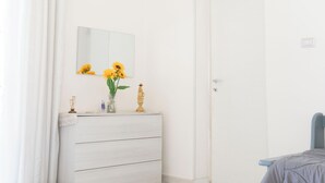 Une chambre à coucher avec un lit, une commode, un miroir et une porte.