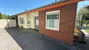 A single-story brick building with a large window, a door, and a small ramp leading to the entrance.