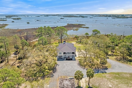 A house with a large porch, surrounded by trees and a body of water.. Bank fishing, kayaks , hiking, bikes ,full gym and old florida personality .