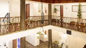 Un interior de varios niveles con un espacio central abierto, barandillas decorativas y zonas de estar.