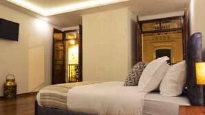 Una habitación de hotel con una cama, un televisor, una lámpara y un adorno en el suelo.