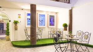 Un patio con zona de estar, plantas en macetas y cuadros en la pared.