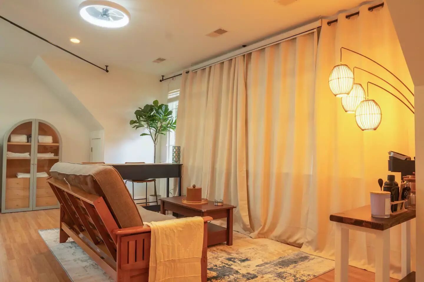 A cozy living room with a sofa, a small table, a piano, and a plant.