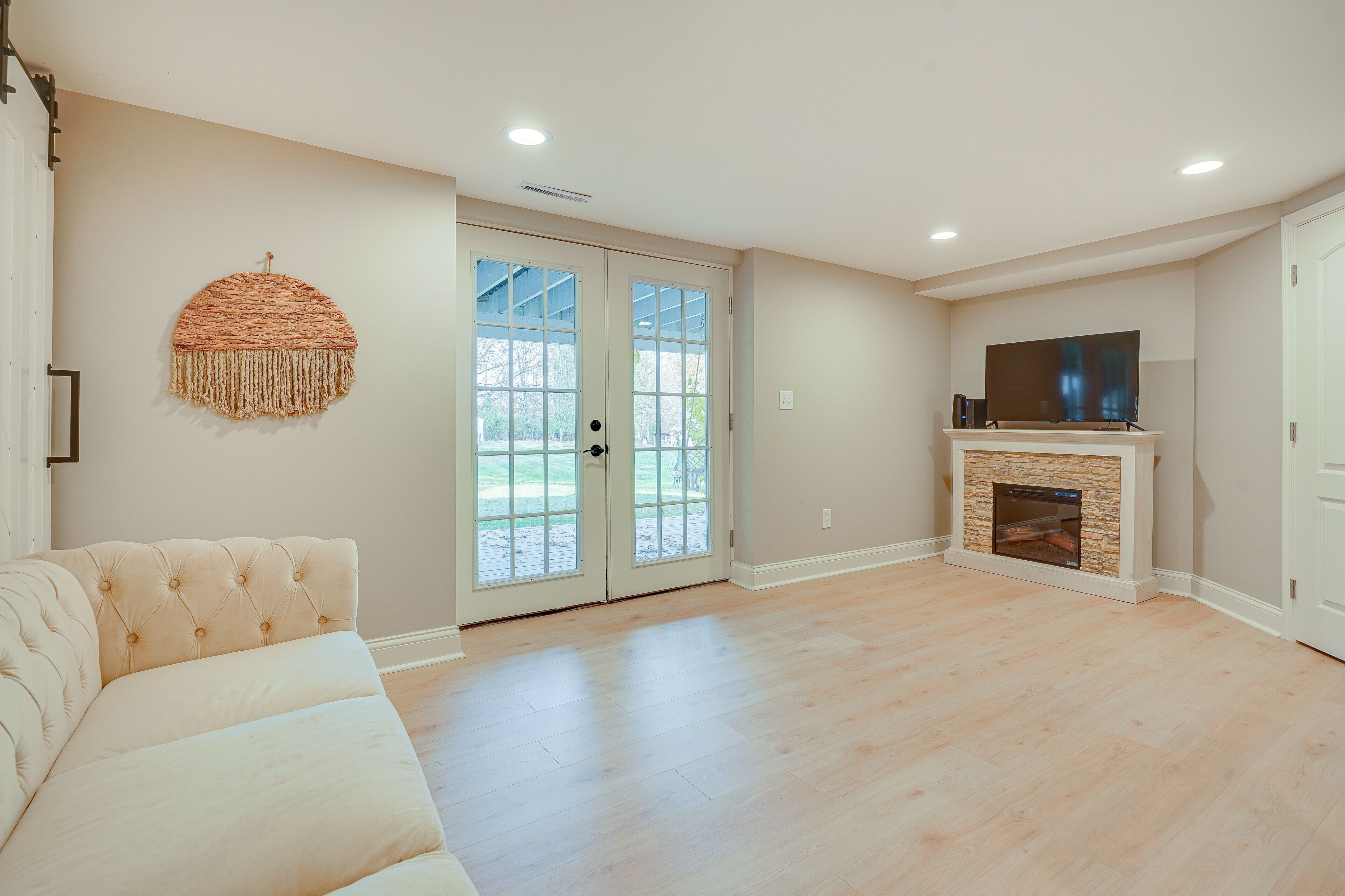A spacious living room with a beige sofa, a fireplace, and a television on a stand.
