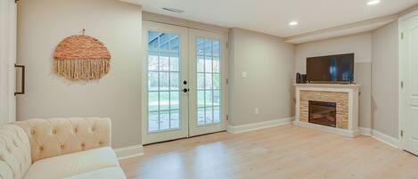 A spacious living room with a beige sofa, a fireplace, and a television on a stand.