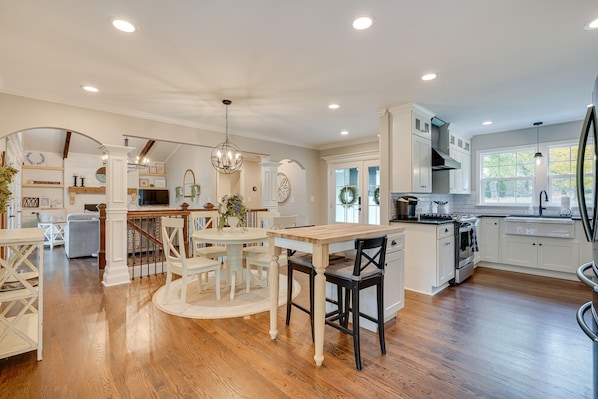 A spacious kitchen with white cabinets, a central island, and a dining area with a round table and chairs.