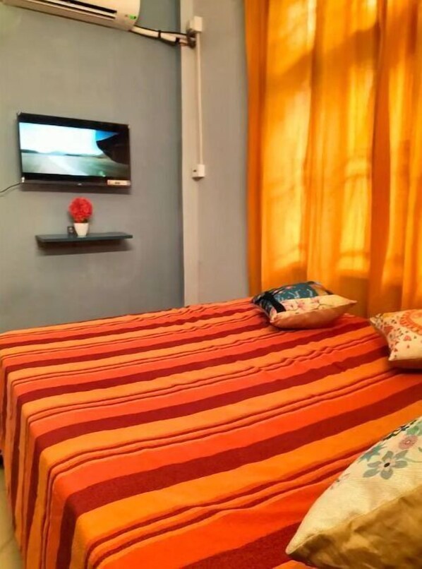 Relax in a stylish room with a comfortable bed, flat-screen TV, and a decorative shelf.