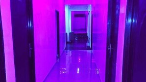 A hallway with a reflective floor and doors on both sides, leading to a bright area at the end. - Premium Hotel & Suites by Victoria Inn (Benin City)