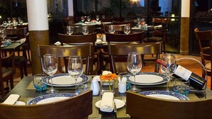 A restaurant with tables set for dining, featuring blue and white tablecloths, and wooden chairs. - Premium Hotel & Suites by Victoria Inn (Benin City)