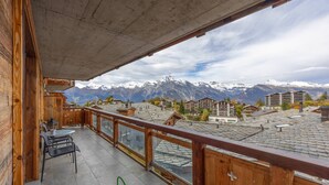 A wooden balcony with a view of snow-capped mountains and a town below. - Montagnard 3 - Spa access (Haute-Nendaz)
