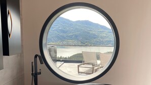 A modern bathroom with a large oval sink and a window overlooking a scenic landscape. - Les Restanques du Lac (Savines-le-Lac)