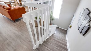 Una sala de estar moderna con piso de madera, barandal blanco y un sofá.