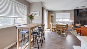 Una cocina moderna con comedor, muebles de madera y televisor montado en la pared.