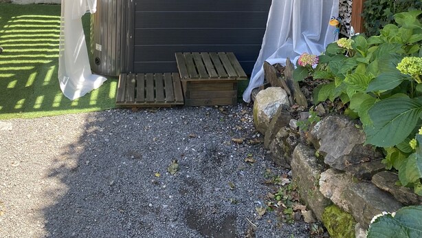 A hot tub under a wooden pergola with white curtains, set against a stone wall with a 'Welcome' sign. - Gîte Dans les Cévennes (L'Estréchure)