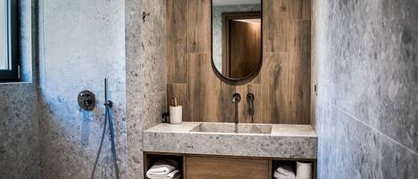 A modern bathroom with a wooden vanity, a large mirror, and a shower area.